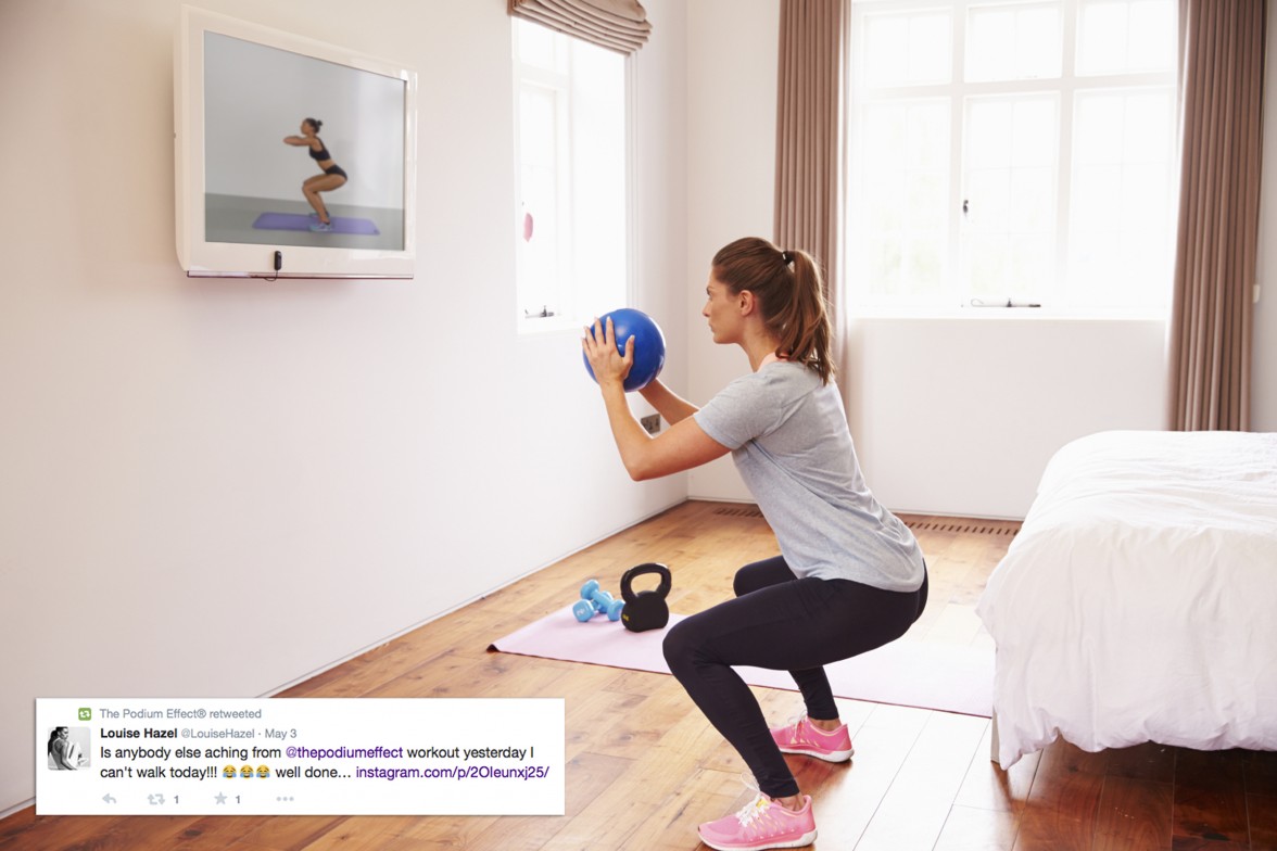 Woman With Ball Working Out To Fitness DVD On TV In Bedroom